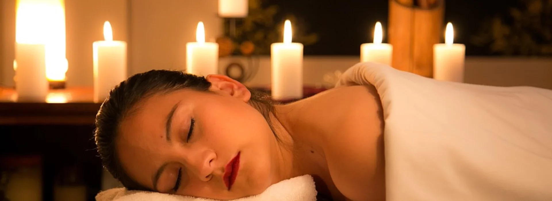 Frau entspannt sich bei einer Massage mit Kerzenlicht – ideal für Wellness und Aleppo Seife Großhandel.